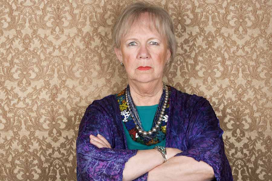 Portrait of skeptical senior woman in front of gold background