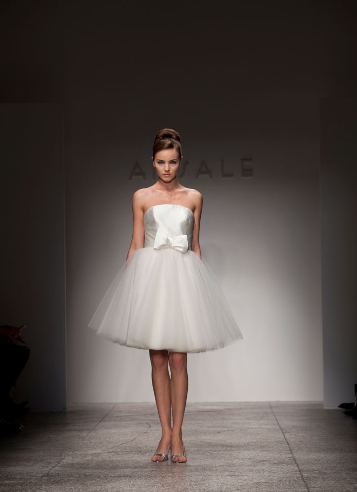 This strapless silk Mikado gown, Tia, is by Amsale and it's the perfect little white dress. It's delicate and feminine but short and chic with its tulle skirt and bow detail at waistline.