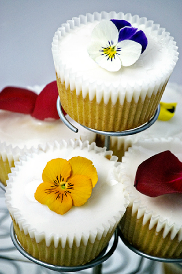Wonderfully festive, these fluffy, champagne cupcakes are accented with crisp white icing and decorated with edible flowers.  Image: Tomayto Tomaaahto
