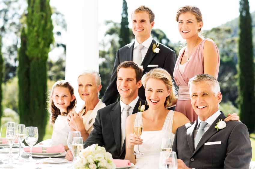 Happy couple with family and wedding guests looking away at reception. Horizontal shot.