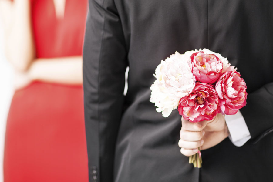 man hiding bouquet of flowers